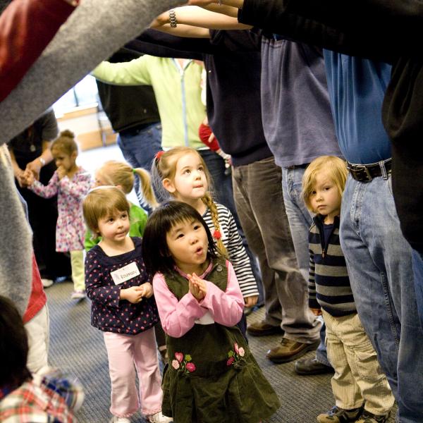 Kids going under a bridge of adult arms. 