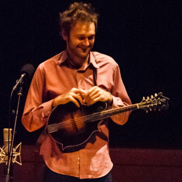 Man smiling holding a mandolin.