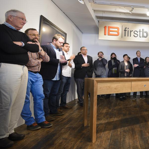 A group of people standing around a newly build table. 