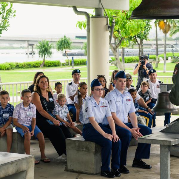 Military families sit on benches outside looking at a National Park Service ranger
