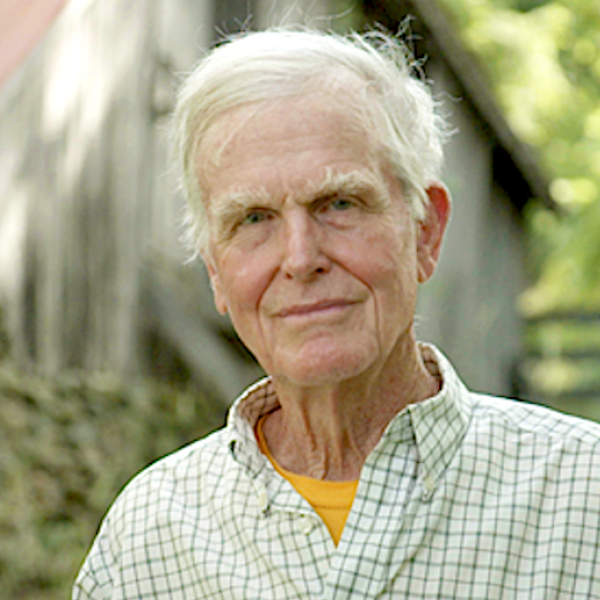 A man poses in front of a barn.