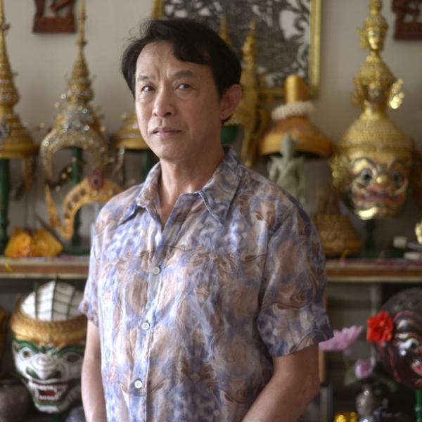 A man standing in front of statuetes on a shelf.