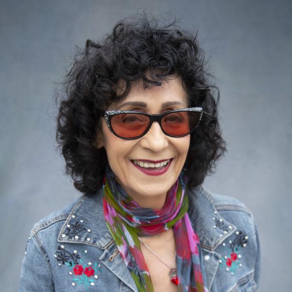 A woman in dark glasses holding a guitar.