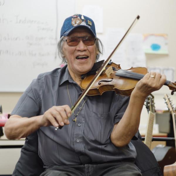 A man plying a fiddle.