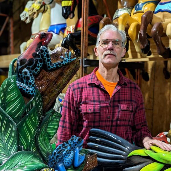 A man surrounded by carousel and carvings.