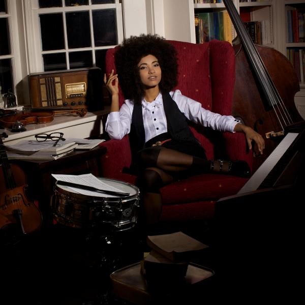 Woman sitting in room surrounded by bass instruments. 