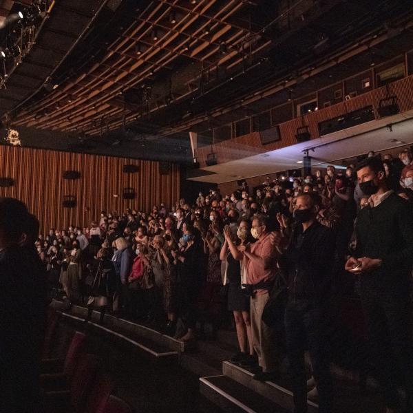 Rows of audience members sitting in a performing arts venue waiting for a performance. 