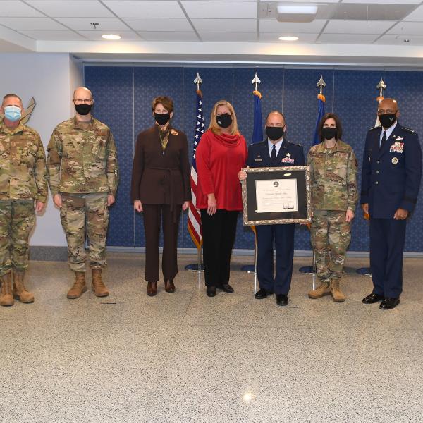Woman standing with military service members, all wearing masks.