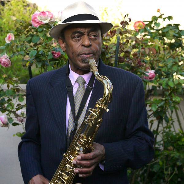 Man in hat holding saxophone.