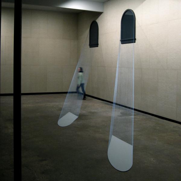 Woman walking through exhibit of wire-created moon rays.