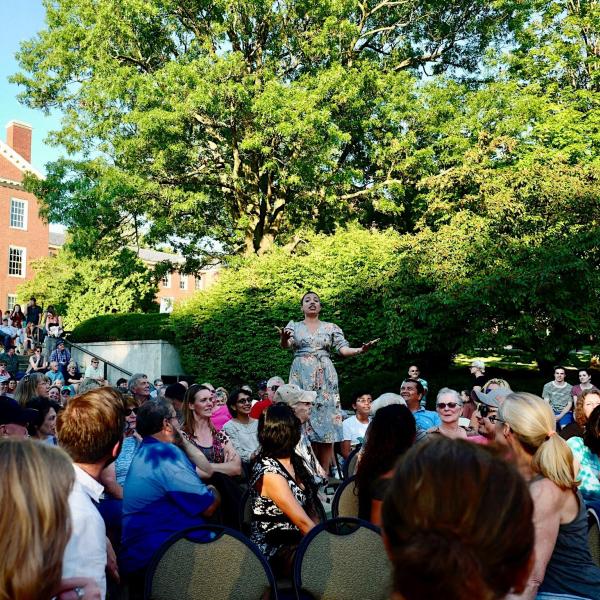 Woman singing in front of large crowd.