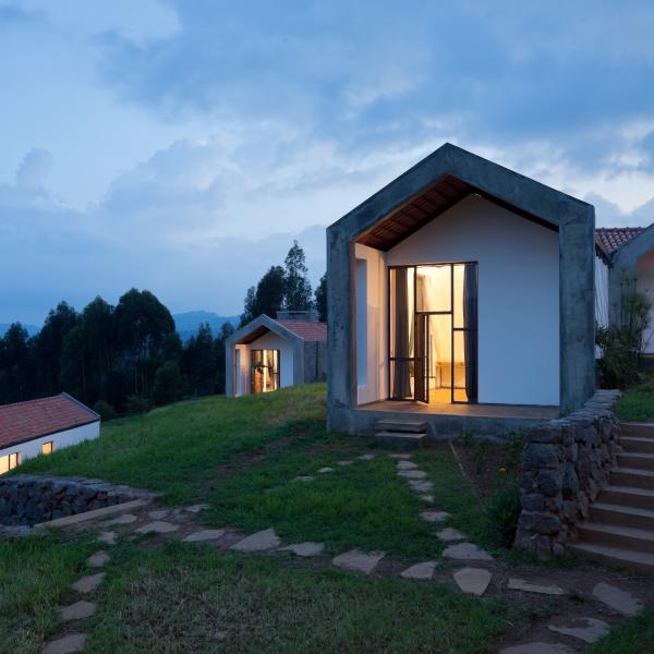 Small housing units lit from within sit atop a grassy hill with stone steps leading up to them