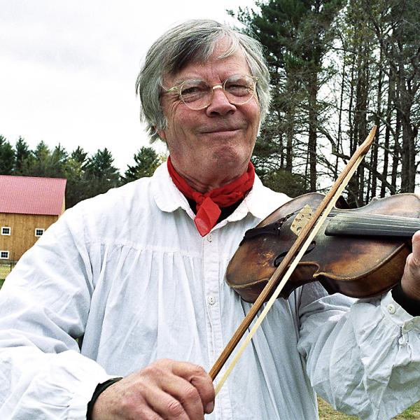 Man playing a fiddle outdoors. 