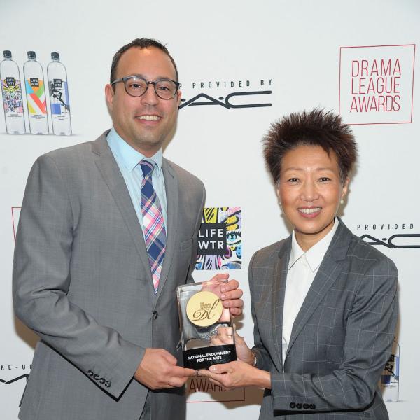 a white man and an Asian American woman hold a trophy