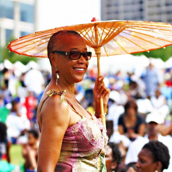 Woman standing outdoors at a festival holding a decorative umbrella.