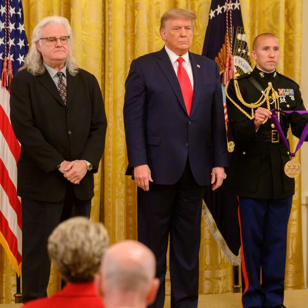 Three men standing in front of US flag. 