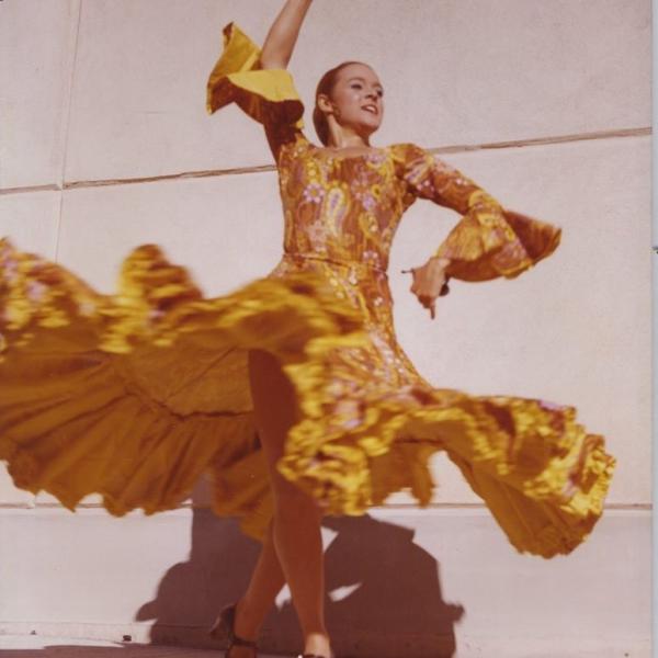 A woman dressed in a flamenco dancer dress strikes a pose.