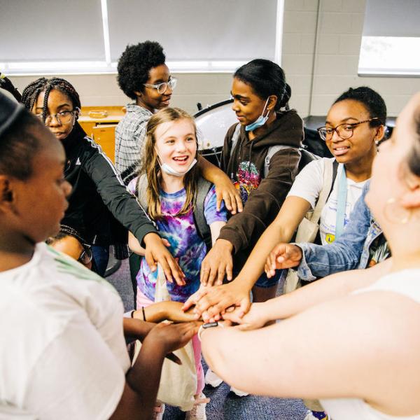 a group of girls stand in a circle with their hands outstretched and joined in the center