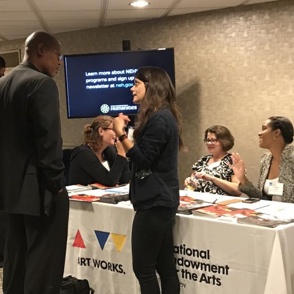 Woman talking to man in front of conference booth. 