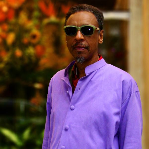 Portrait of man in purple shirt wearing sunglasses.
