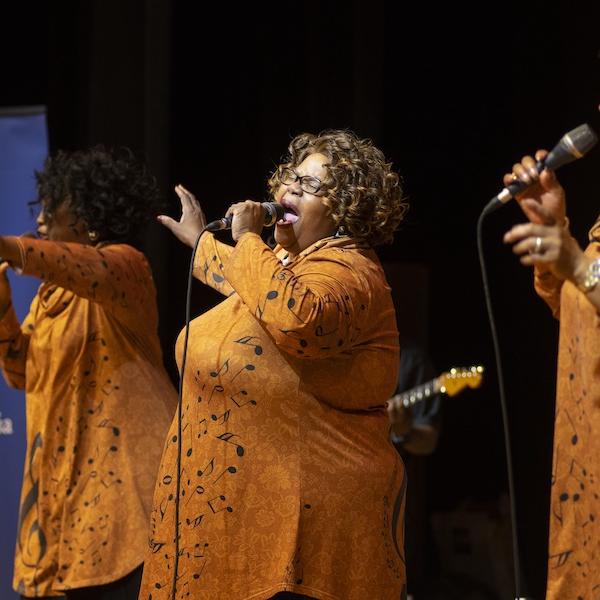 Three women singing on a stage.