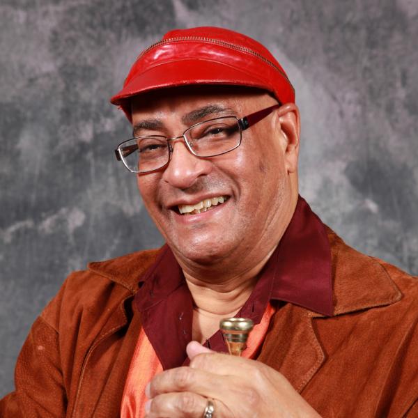 Portrait of man in red hat holding trumpet. 
