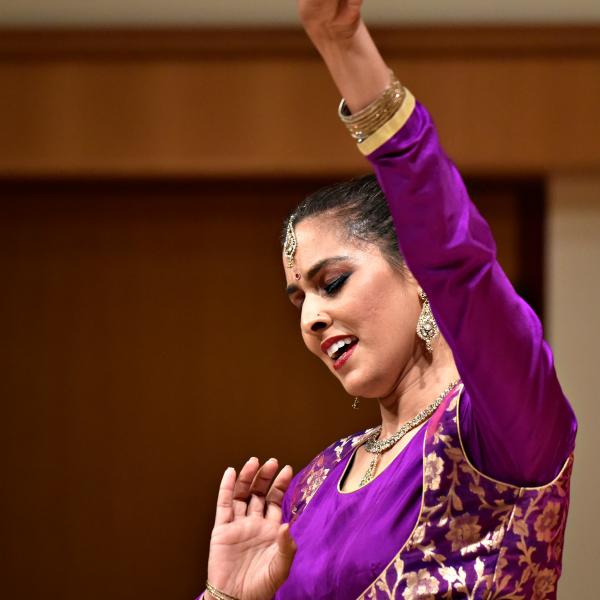 Indian American woman in purple outfit dancing.