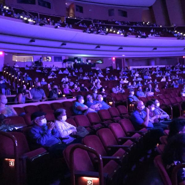 People seated in a theater wearing masks