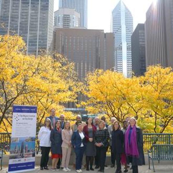 a group of people pose for a photo against a background of trees with yellow leaves