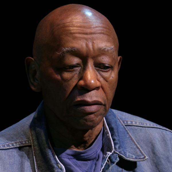 Bald black man in a blue shirt looking down. 