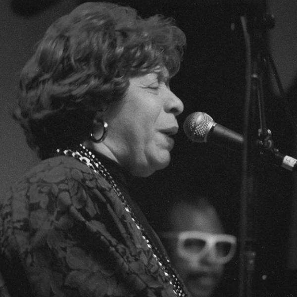 Woman at piano, singing. 