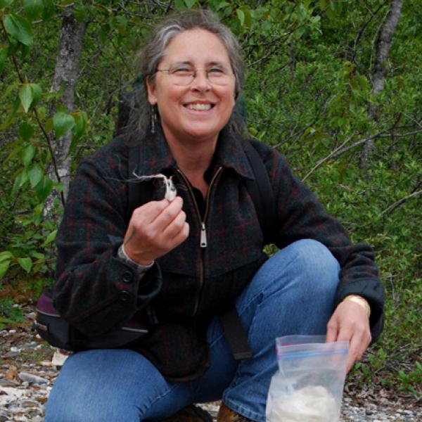 Woman on beach holding wool. 