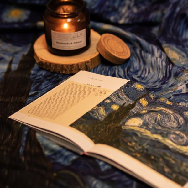 Photo of Vincent van Gogh's painting The Starry Night with a candle lit beside it.