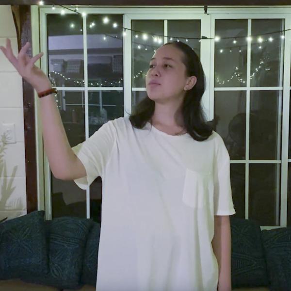 Woman in white shirt looks towards hand held to sky