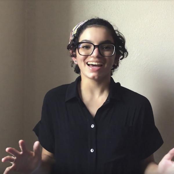 Smiling woman in black shirt speaks with open arms