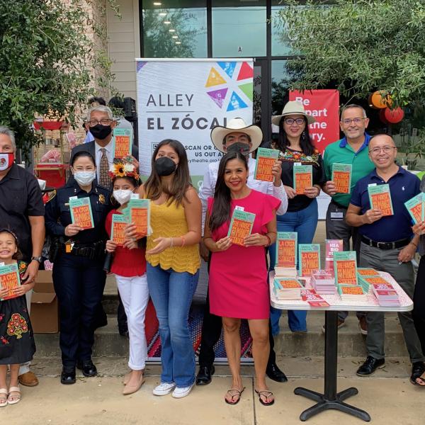 A group of people stand outside holding copies of The House on Mango Street