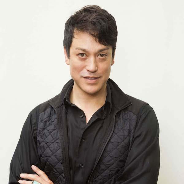 A man with crossed arms faces the camera.