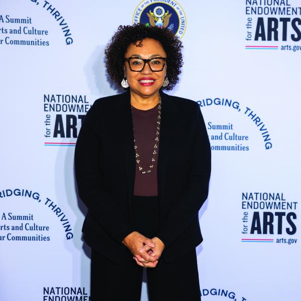 Woman wearing glasses standing in front of a banner.