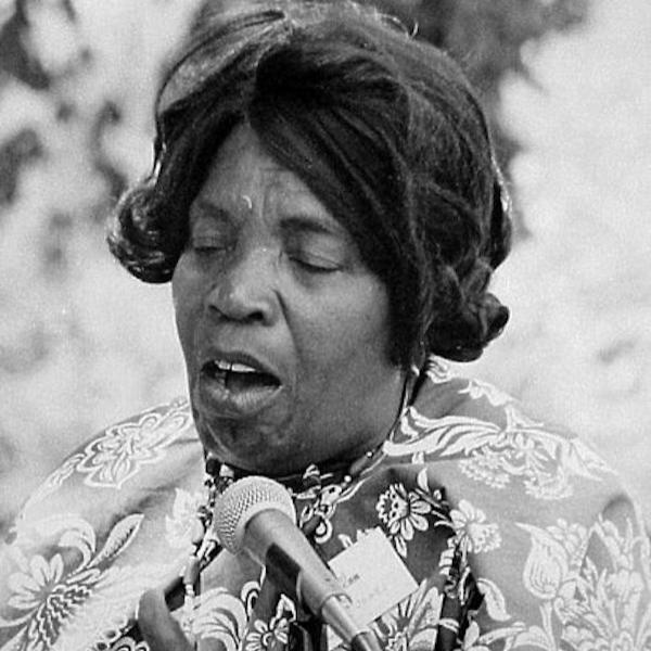 Woman sings into a microphone.