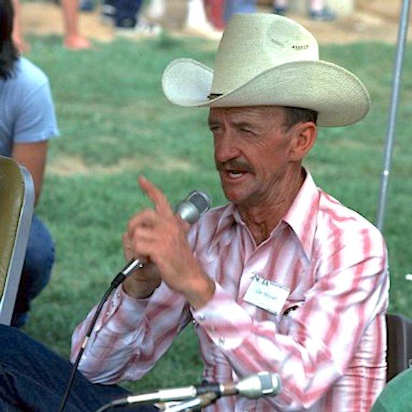 A man with a hat speaking into a microphone.