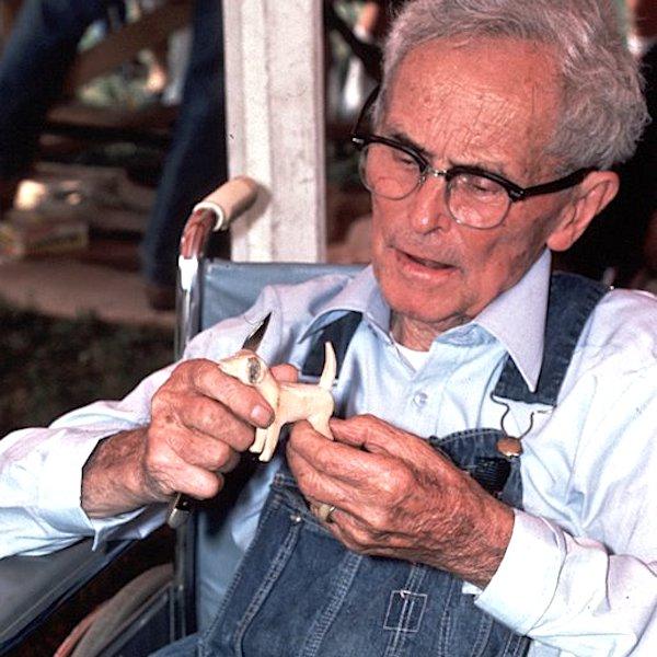 A man holding a small wood figurine.
