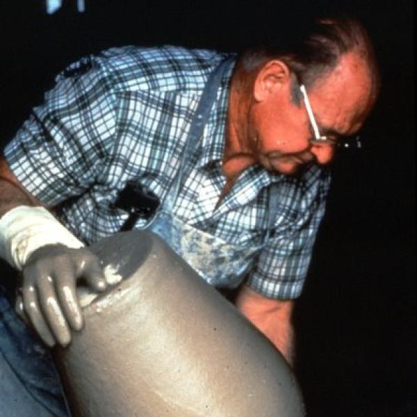 A man holding a cly pot.