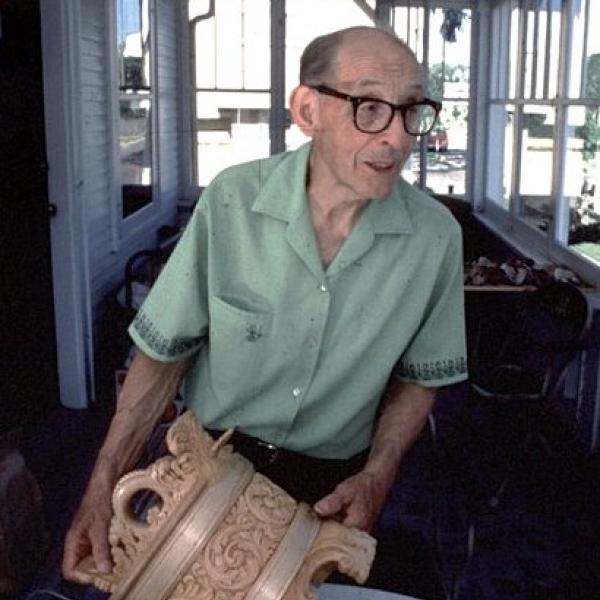A man holding a carved wooden piece.