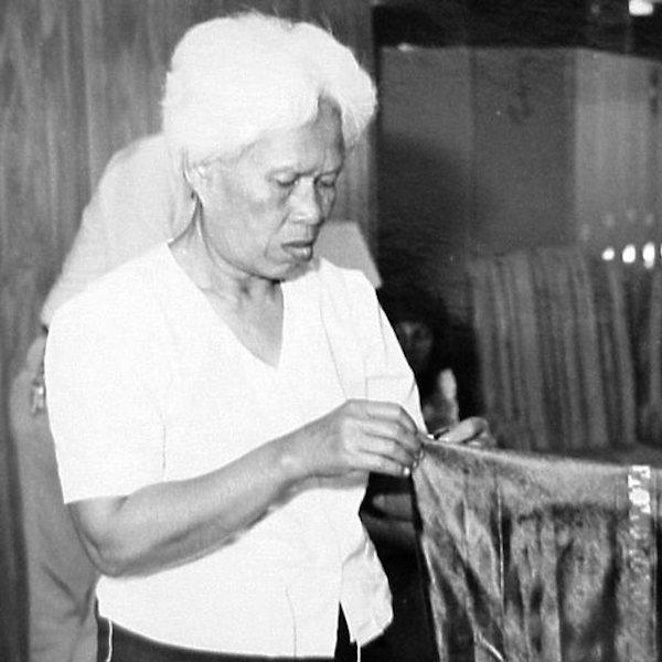 A woman holds a piece of  cloth.