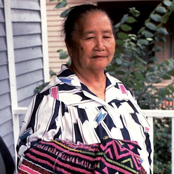 A woman holding weavings on her forearm.