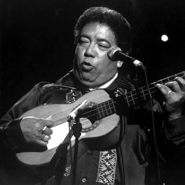 A man playing a guitar and singing from a stage.