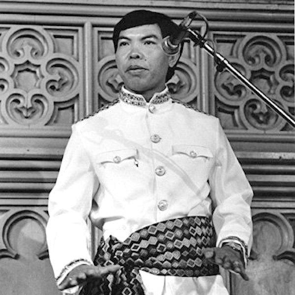 A man in traditional dress gestures with his hands.