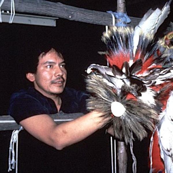 Man holding up a feather headdress.