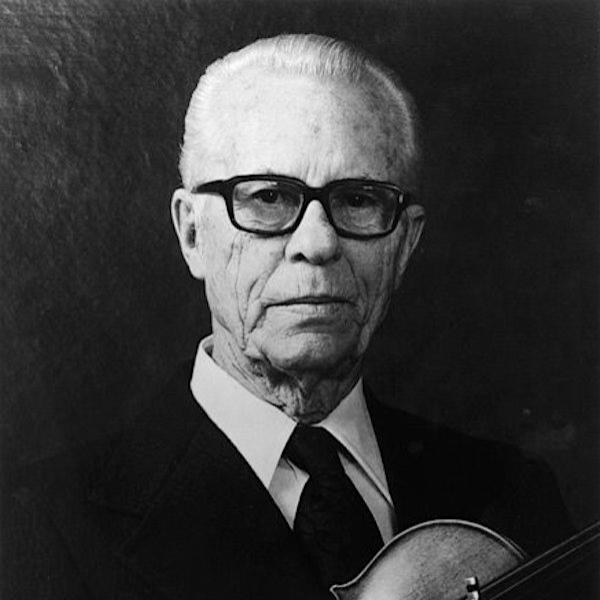 A man poses with a violin in his arms.