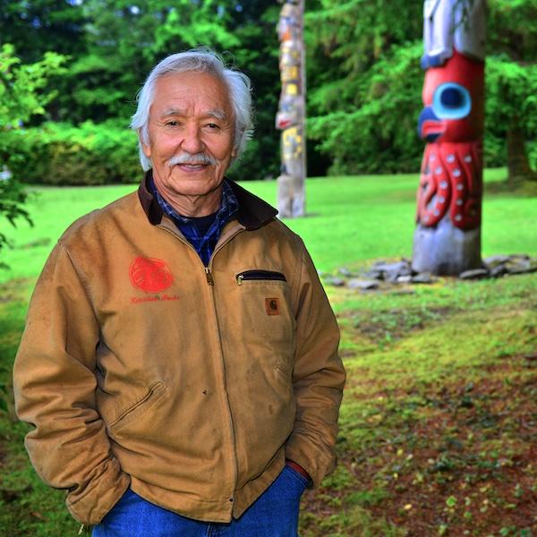 A man poses near a totem.